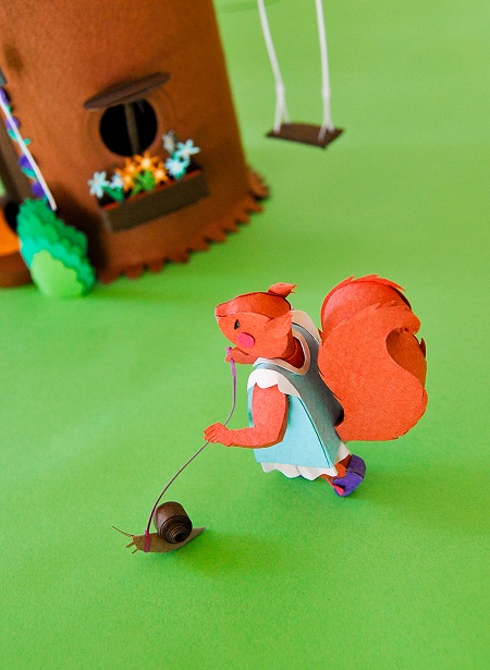 Paper art - The little squirrel walks his snail next to the swing. Miniature.