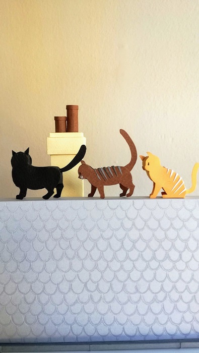 Paper art - Three of the diorama cats in single file on a gable roof. Detail.