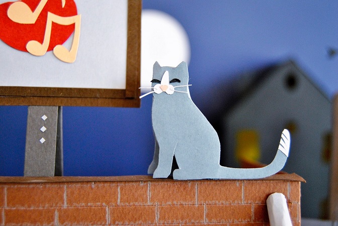 Paper art - Cat smiles on a rooftop overlooking the view. Diorama detail.