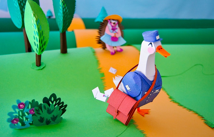 Paper art - The duck that delivers the mail in the forest continues its way without realizing that it is losing some cards in its path. Paper sculpture.