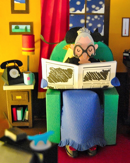 Paper art - Grandma reading the newspaper in the living room. Paper sculpture.