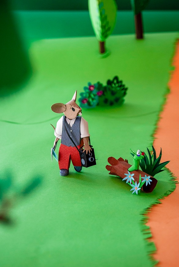 Paper art - The mouse journalist passes through a forest clearing next to the trunk of a nice worm. Paper woods diorama.