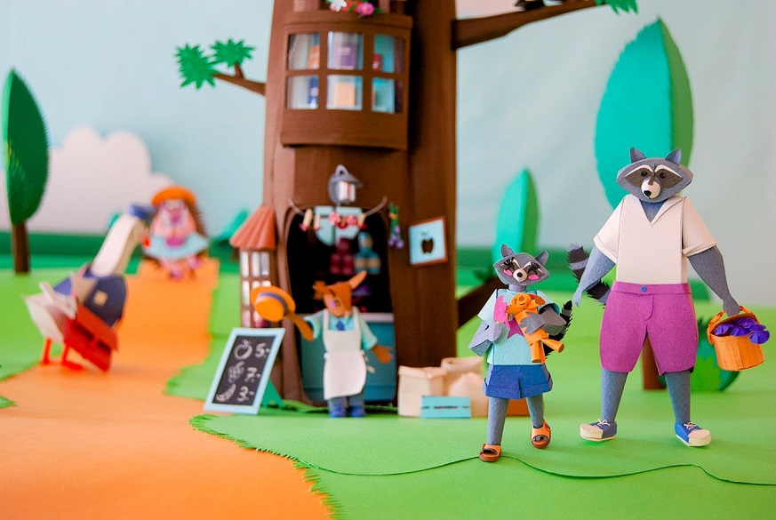 Paper art - The raccoon customers walk away from the store while the clerk mouse greets them gratefully for the purchase. Paper diorama.